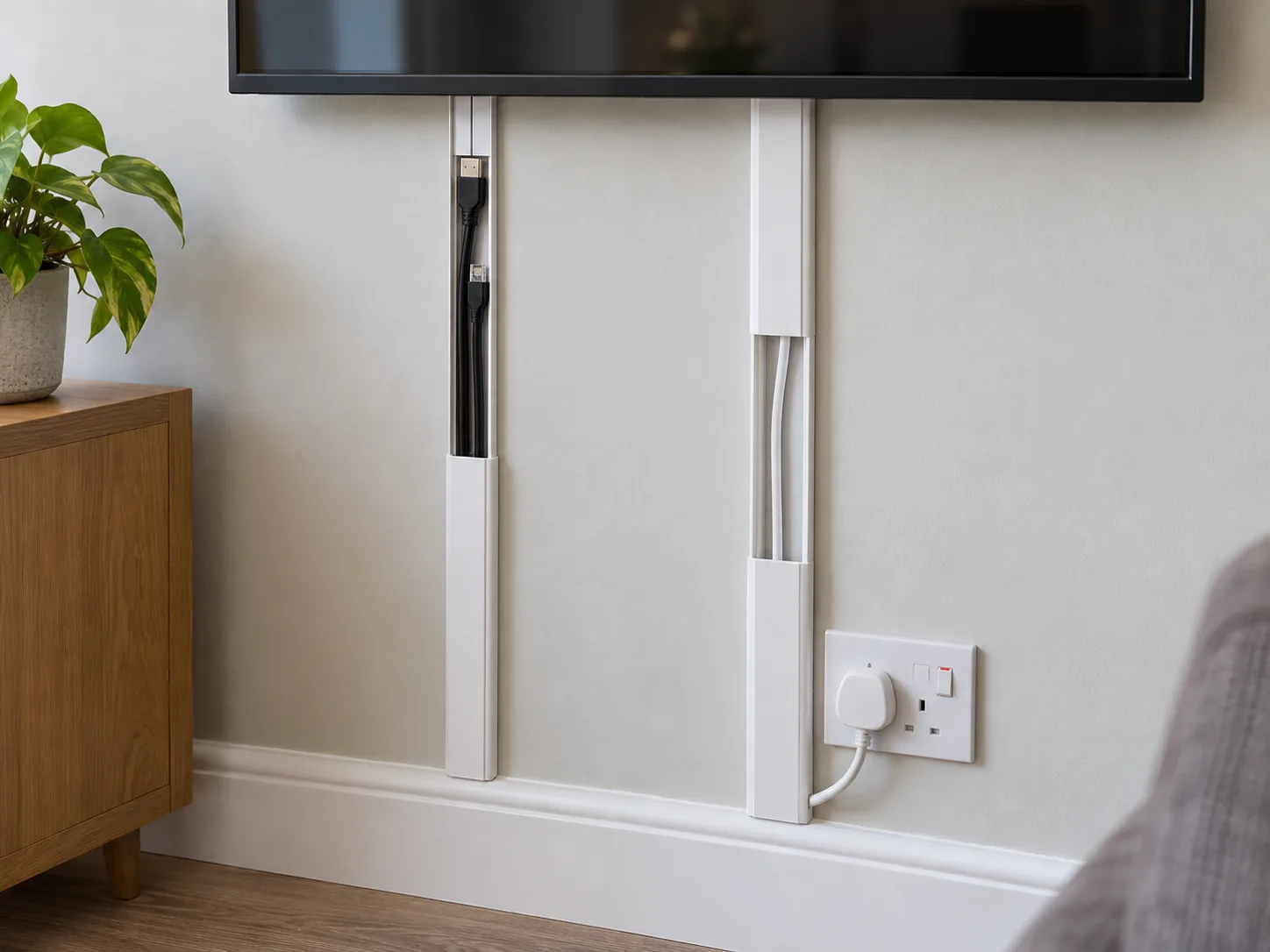 Separate surface trunking routes for HDMI leads and a TV mains flex beside a UK socket